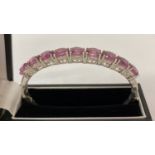 A silver hinged bangle set with 9 oval cut pink fluorite stones by TJC.