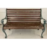 A wooden slatted garden bench with cast iron bench ends painted green and with lions head detail.