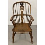 An antique elm seated spindle back Windsor armchair with carved back panel and turned legs.