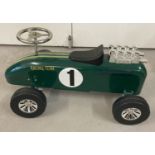 A vintage style children's ride on metal racing car, painted green.