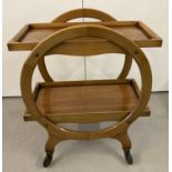 A light wood Art Deco 2 tier drinks trolley with circular frame and fixed shelves.