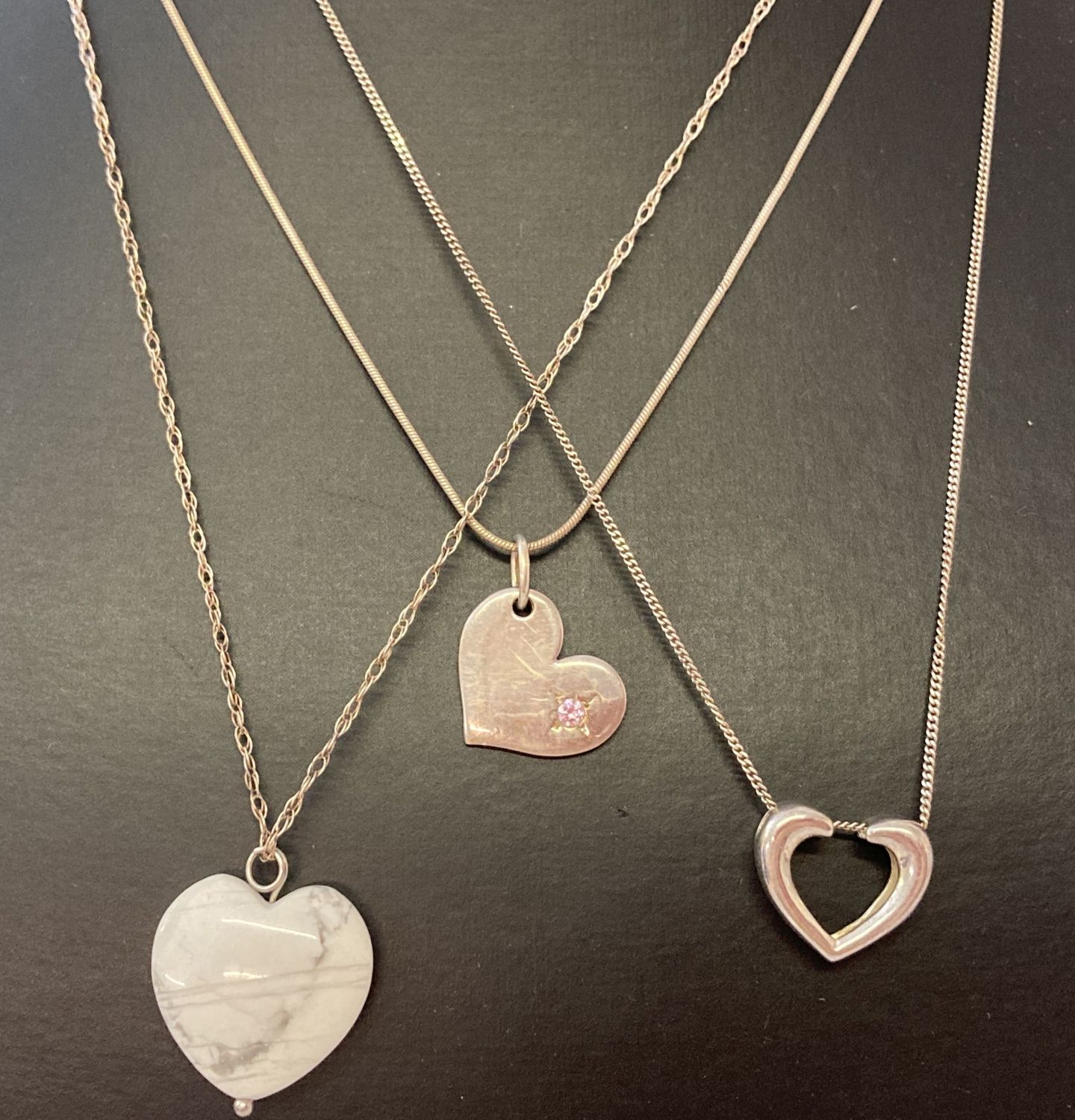 3 silver and white metal heart design necklaces.