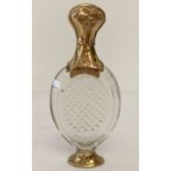 A cut glass scent bottle with gold foot and hinged lid.