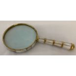 A brass bound magnifying glass with mother of pearl detail.