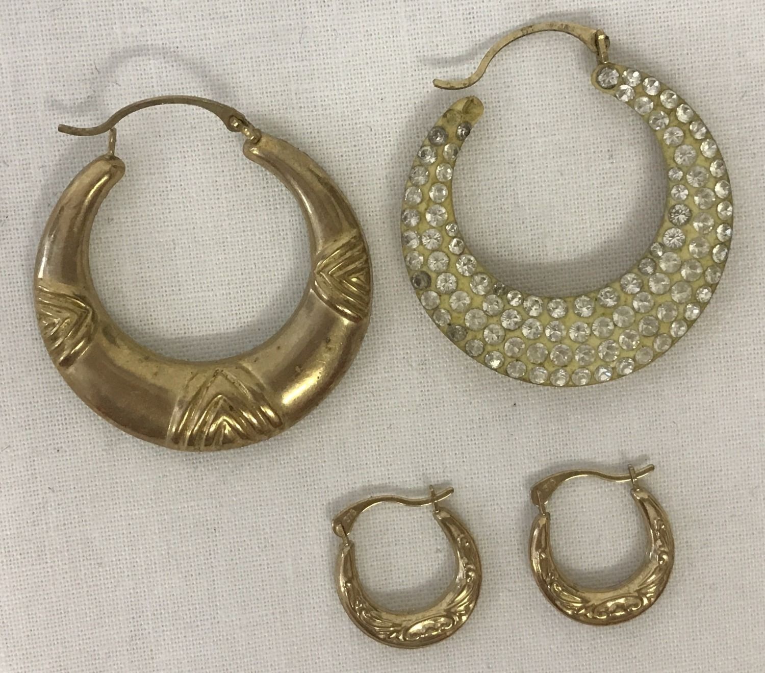 2 pairs of hoop style earrings. A larger pair set with clear stones to one side.