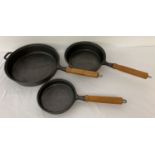 A set of 3 modern wooden handled cast iron skillet pans. 6, 8 and 10 inch diameters.