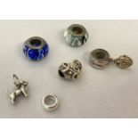A small collection of silver, white metal and glass charms and charm beads.