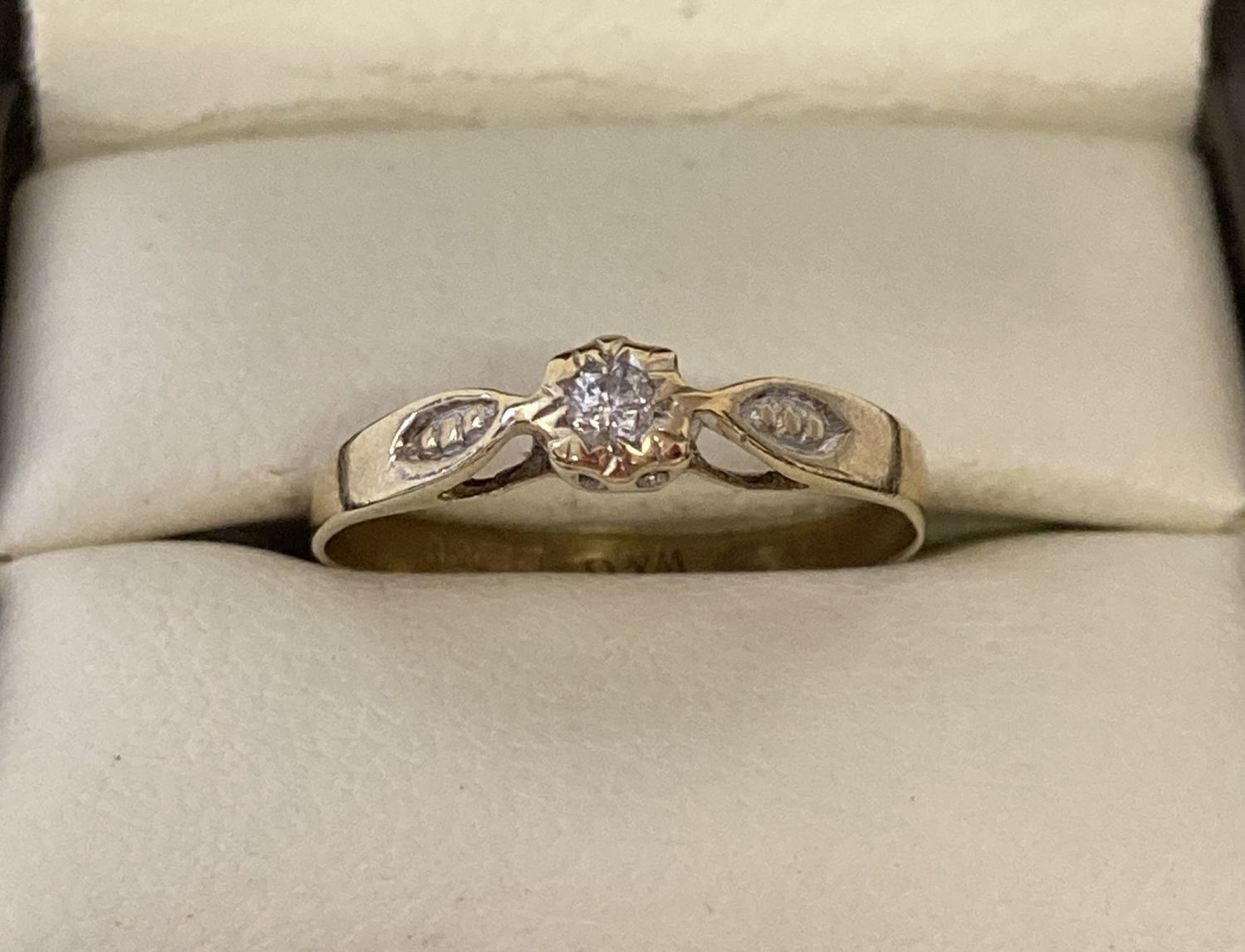 A 9ct gold diamond solitaire ring with detail to shoulders. Stone size approx. 0.07ct.