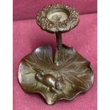 A small bronze candle holder in the form of a frog on a lily pad.
