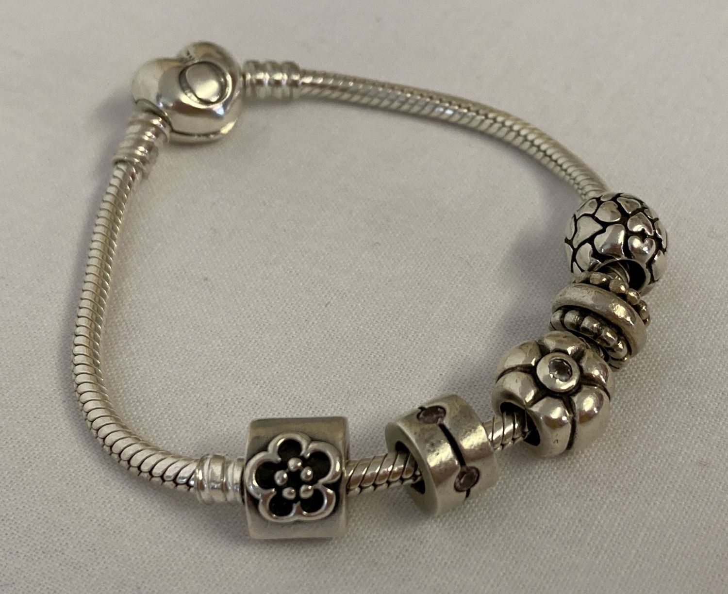 A Pandora charm bracelet with heart shaped clasp and 5 charms.