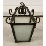 A vintage hanging porch lantern. Metal with 4 glass panels. Scroll detail to top.