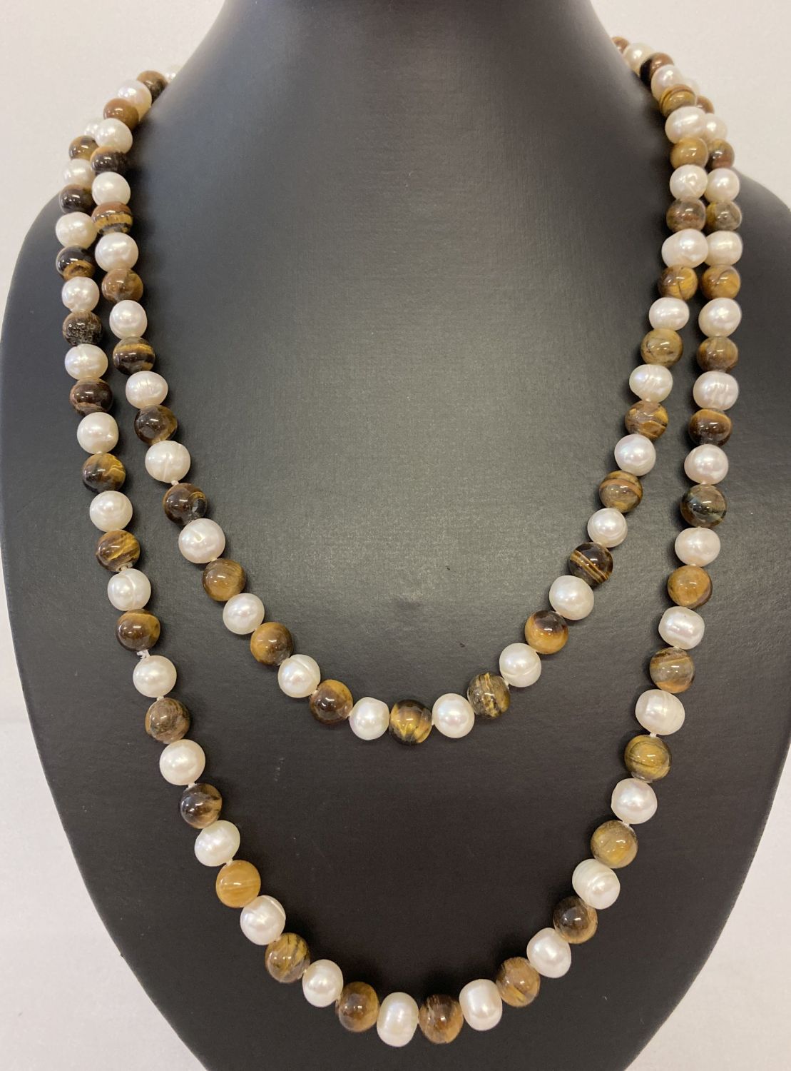 A 44" string beaded necklace of alternate cream fresh water pearls and Tigers eye beads.