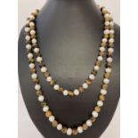 A 44" string beaded necklace of alternate cream fresh water pearls and Tigers eye beads.