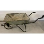 A vintage galvanised wheelbarrow with cast iron wheel and rubber handle grips.