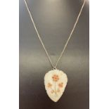 A carved shell pendant set with small pieces of coral and turquoise on a silver 18" box chain.