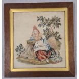 An oak framed and glazed antique tapestry of a woman in period dress sitting under a tree.