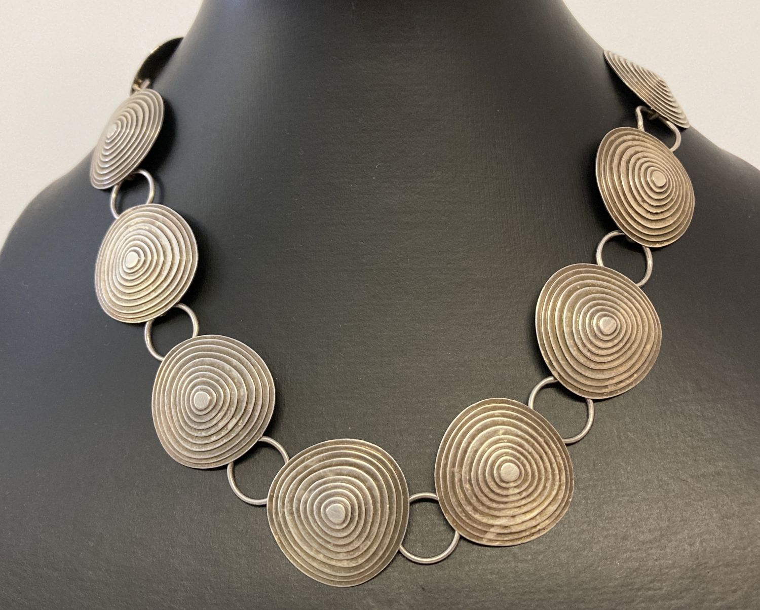 A vintage 16" white metal statement necklace with 12 concentric circle pendants.