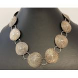 A vintage 16" white metal statement necklace with 12 concentric circle pendants.