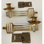 A pair of Arts and Crafts brass wall mountable candle sconces, complete with fixing plates.