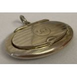 An oval shaped silver pill/snuff box with engine turned decoration. Small mirror to inside of lid.