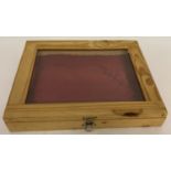 A pine cased table top display cabinet with red satin lined interior, glass panel top and hinged lid