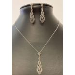 A silver drop pendant necklace and matching drop style earrings.