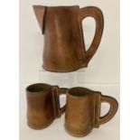 A leather jug with two leather drinking mugs with bold stitching.