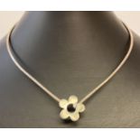 A silver torque style necklace with flower clasp to front. Marked 925 to back.