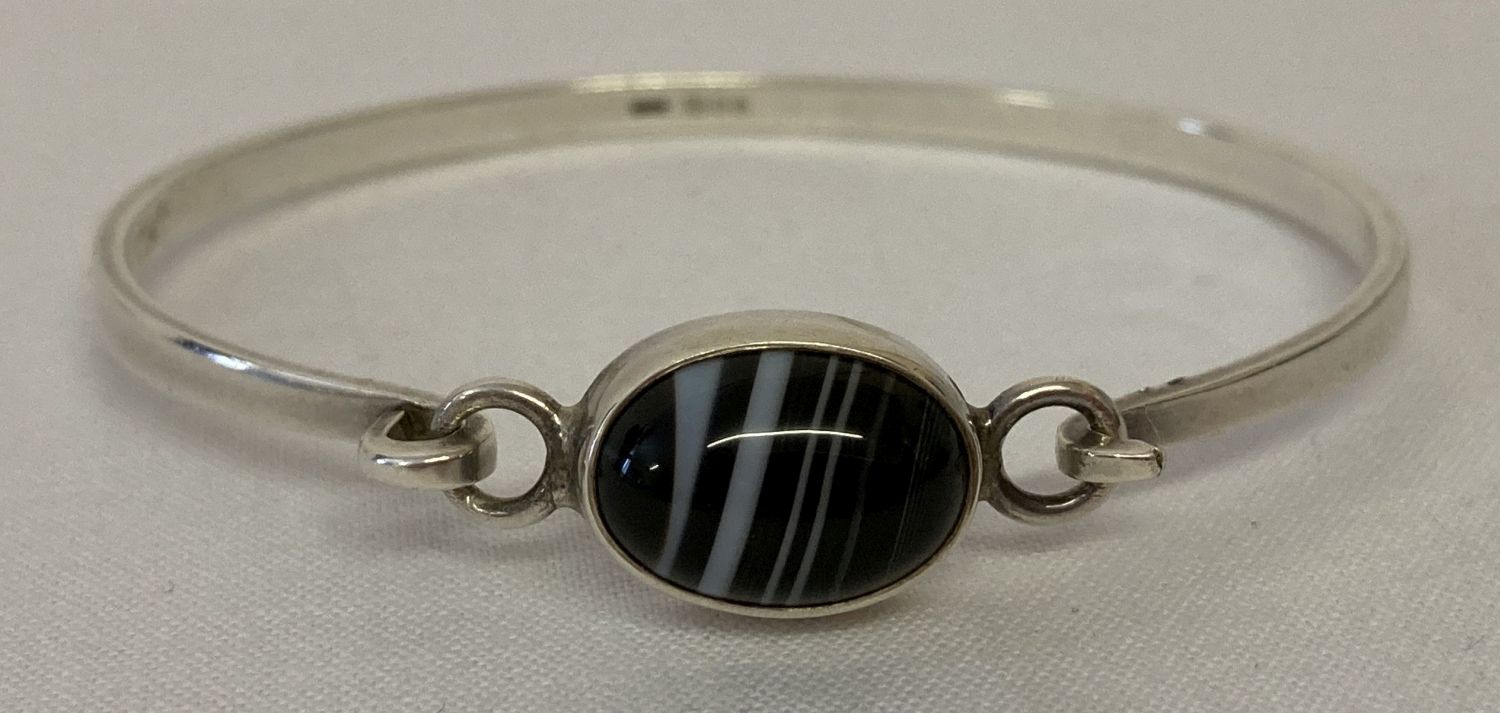 A vintage silver bangle set with a black banded agate stone.