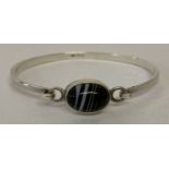A vintage silver bangle set with a black banded agate stone.