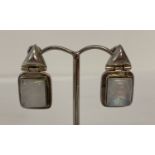 A pair of modern design silver drop earrings set with square cut moonstones.