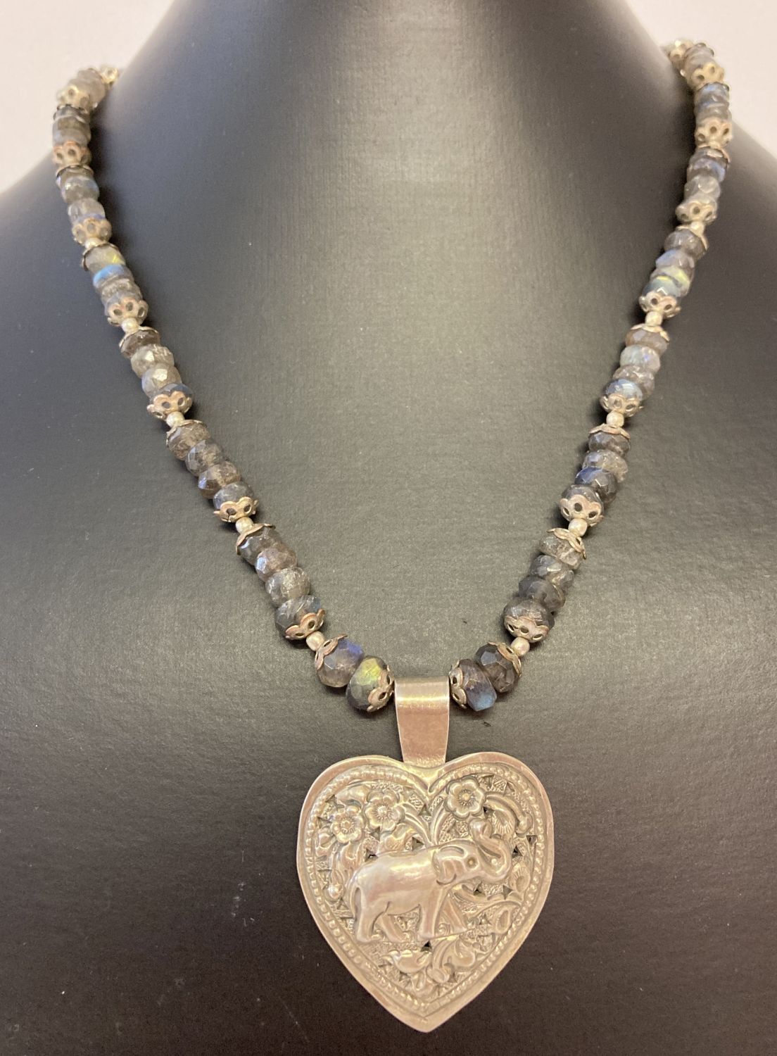 An ethnic style necklace of labradorite and white metal beads with a silver heart shaped pendant.