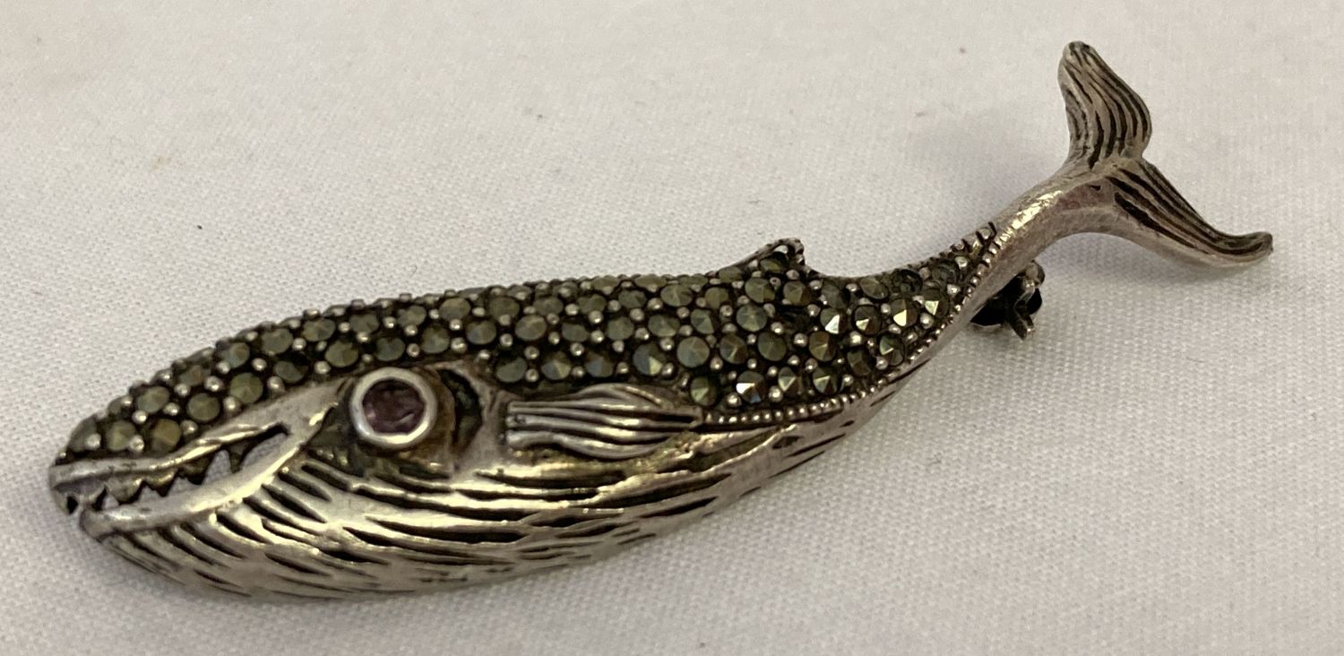 A silver brooch in the shape of a whale set with marcasite stones and an amethyst set eye.