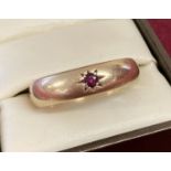 A 9ct gold men's band style ring set with a single small round cut ruby.