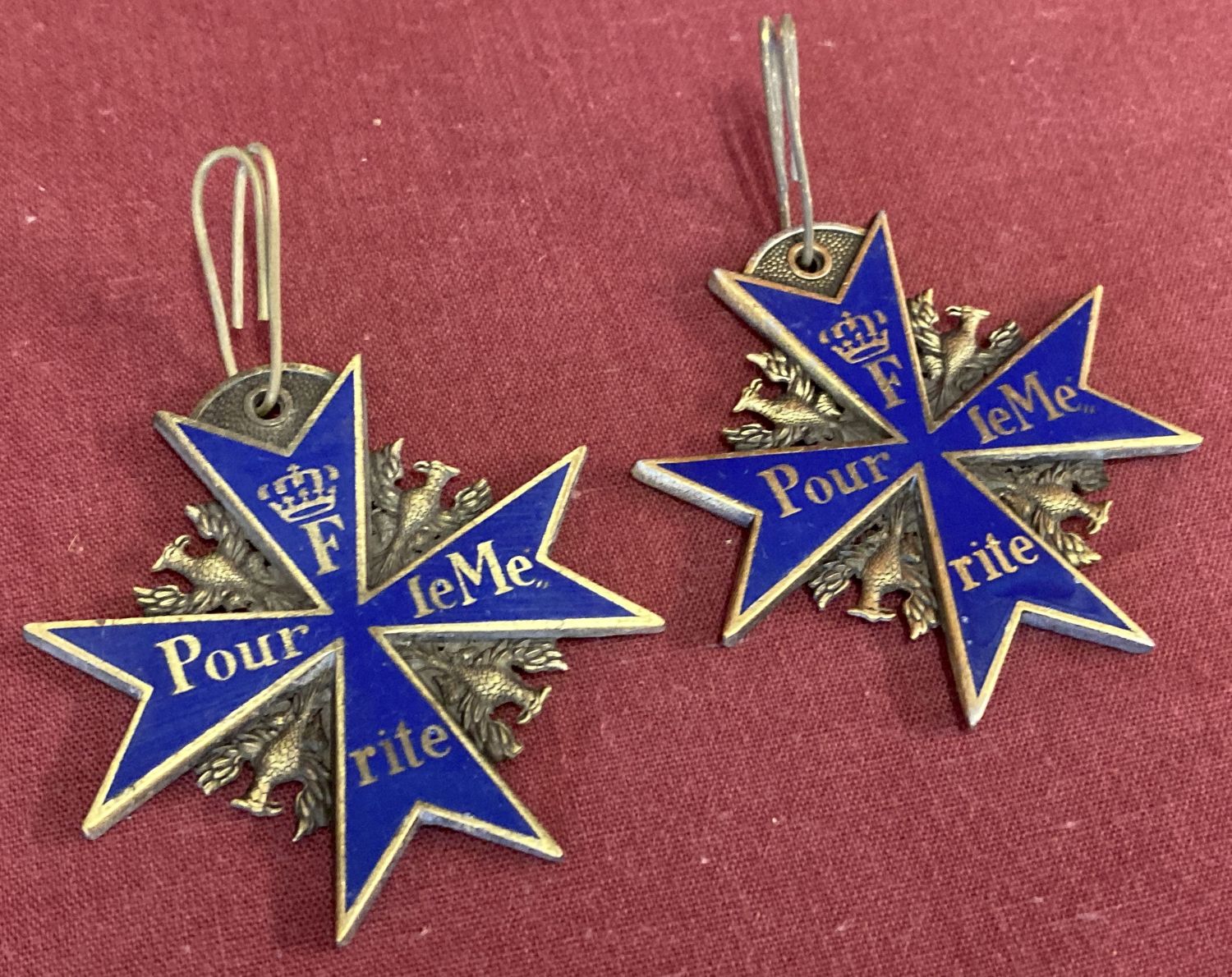 2 reproduction Pour Le Merite medals with blue enamel finish and eagle detail.