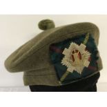 A Royal Scots green felt Tam "O" Shanter complete with cap badge on a hunting Stuart tartan patch.