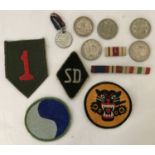 A badge of assorted military embroidered patches, ribbons and coins.