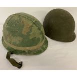 A US M1 steel helmet with camo cover and elastic cover band.