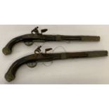 A pair of antique Middle Eastern brass framed flintlock pistols with ornate foliate designs.