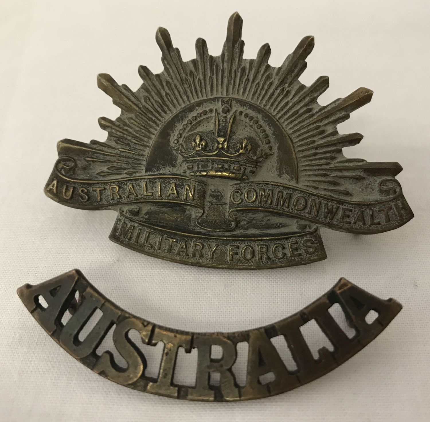 A WWI style Australian Rising Sun cap badge and shoulder title.