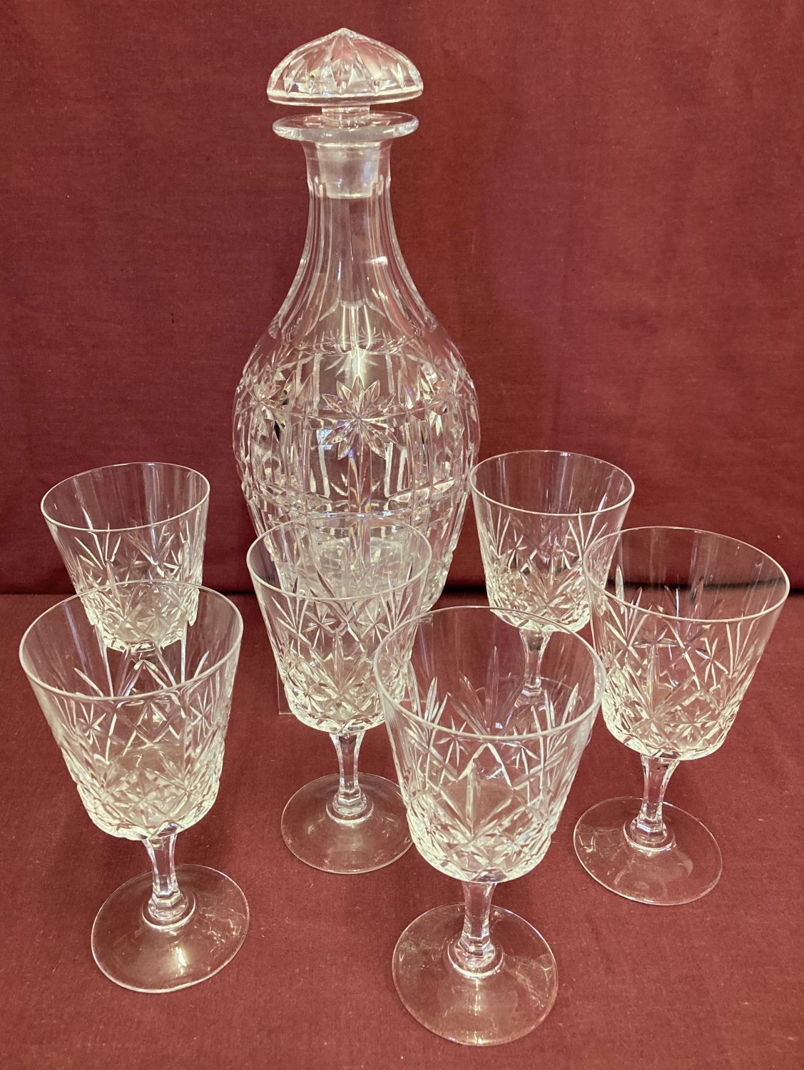 A heavy cut crystal decanter together with a set of cut glass stemmed glasses.