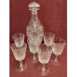 A heavy cut crystal decanter together with a set of cut glass stemmed glasses.