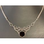 A silver Art Deco style necklace set with central hexagon cut onyx stone and small marcasite stones.