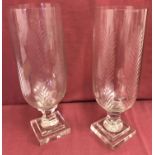 A pair of cut glass vases raised on pedestal stems with engraved detail.