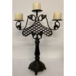 A black painted cast iron candelabra with lattice and leaf decoration.