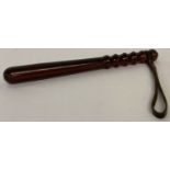 A wooden truncheon with leather carry strap.