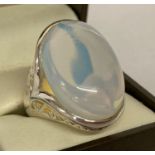 A 925 silver dress ring set with large opal glass cabochon & with pierced work detail to shoulders.