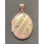A 9ct tri colour gold oval locket with engraved detail to front.