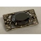 A vintage silver brooch with ivy detail and central oval cut hematite stone.