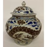 A large Chinese ceramic lidded temple jar with hand painted blue and brown dragon design.